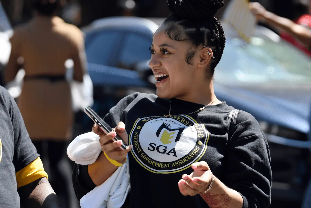 female student with SGA t-shirt holding a phone